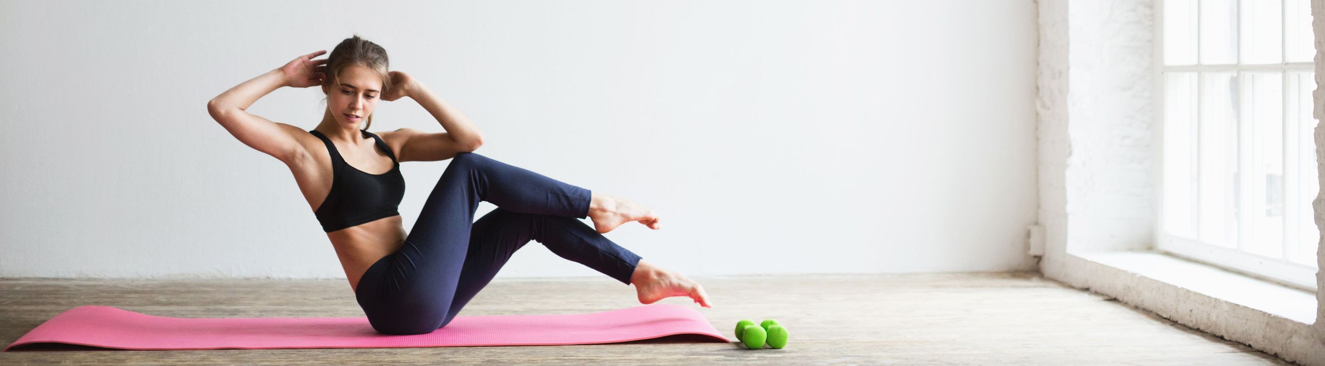 Sportliche Frau macht Butterfly Sit-Ups auf einer Yoga-Matte